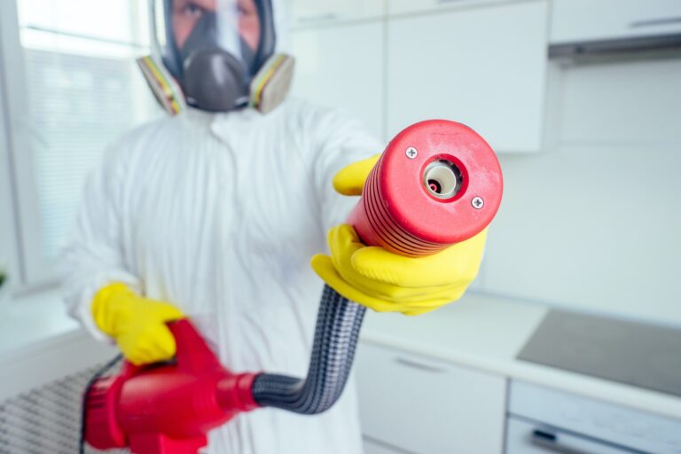 pest control worker standing with sprayer in kitchen